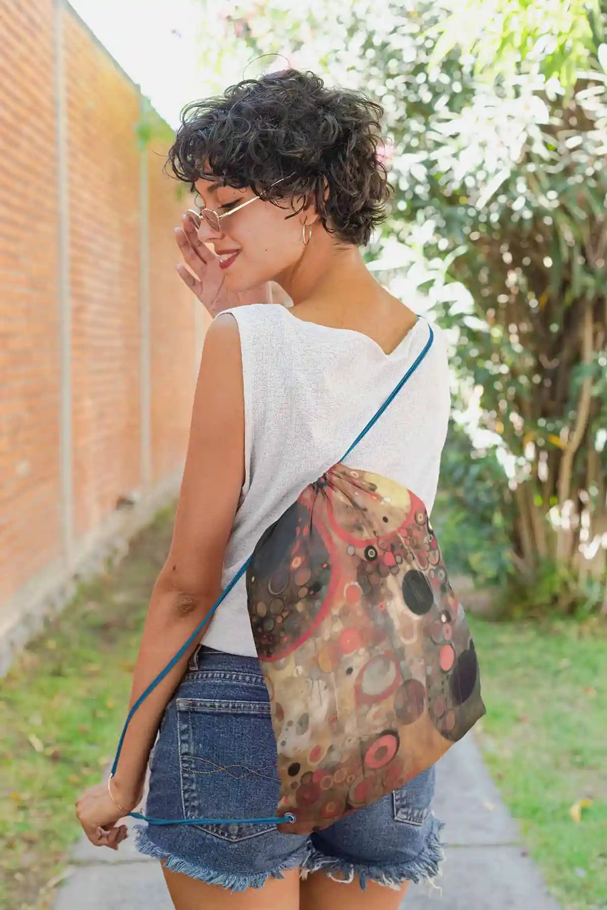 Sacred Serenade digital art print on a drawstring bag featuring a short-haired girl looking over her shoulder.