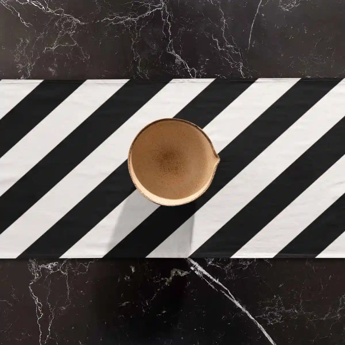 Diagonal Stripes digital art print on a table runner placed on a marble table featuring a vase.
