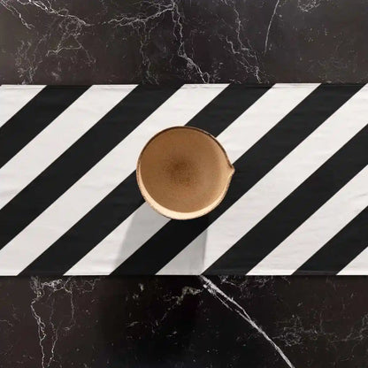 Diagonal Stripes digital art print on a table runner placed on a marble table featuring a vase.