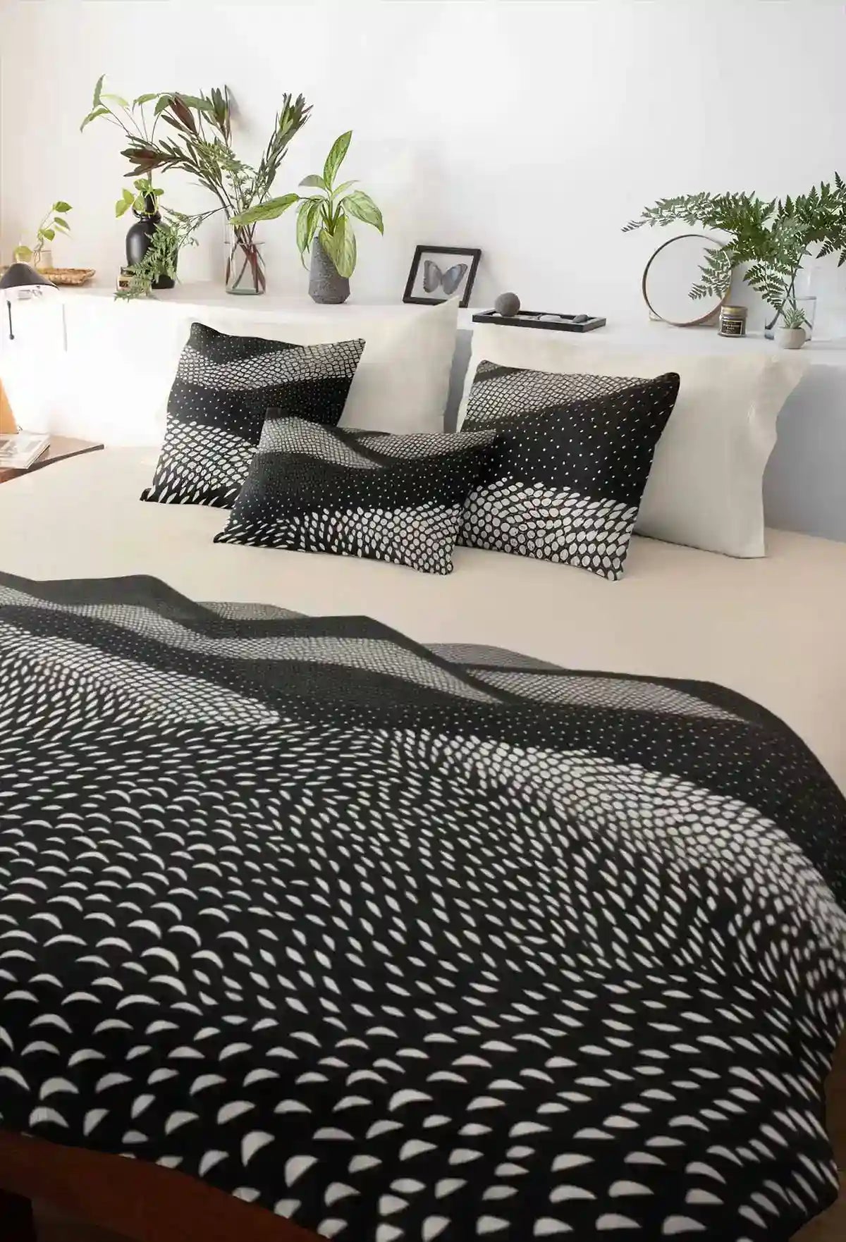 Mountains digital art print on duvet cover with a few pillows on a bed, featuring abstract black and white rolling hills.