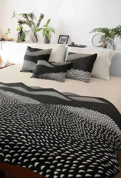 Mountains digital art print on duvet cover with a few pillows on a bed, featuring abstract black and white rolling hills.