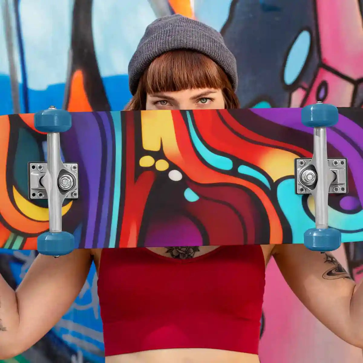 Skateboard featuring Multivue digital art print held by skater woman near graffiti wall.