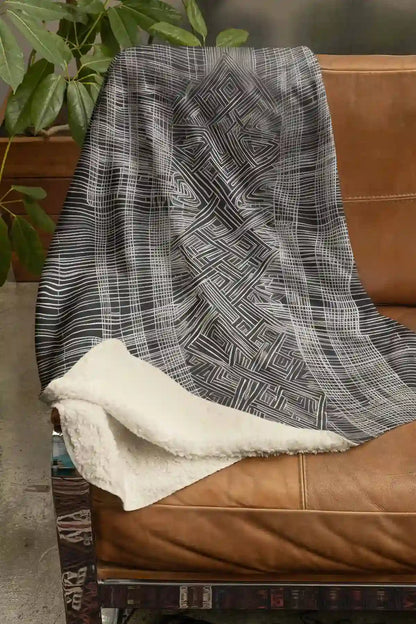 Soulprint digital art print on a Sherpa fleece blanket placed on a couch, featuring intricate geometric patterns and abstract art, adding a stylish and modern touch to the living space.