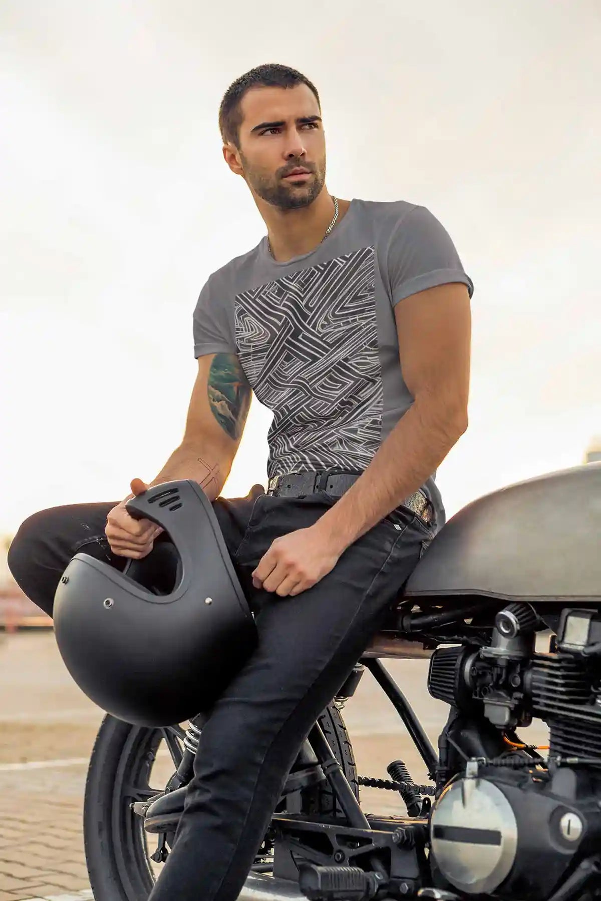 Soulprint digital art print on a round neck tee worn by a tattooed stylish man posing on a bike, featuring intricate geometric patterns and contemporary art design, adding a bold and modern style.