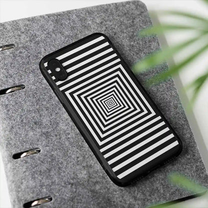 Squares digital art print on a clear phone case placed by a plant, featuring bold concentric black-and-white squares, adding a modern and artistic touch to the scene.