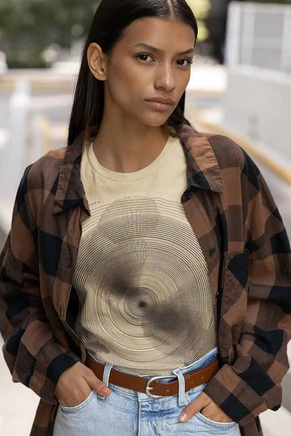 Woman wearing a plaid shirt over a beige t-shirt with a circular pattern.