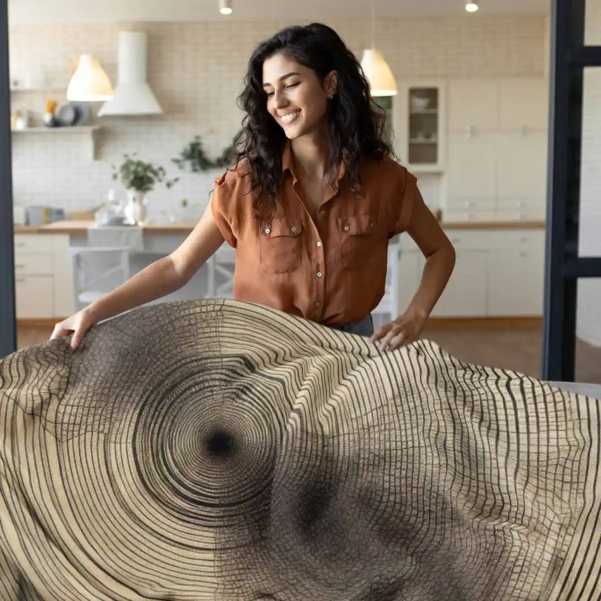 Tidal Orbits digital art print on a sublimated fleece blanket featuring a woman putting it on a couch, adding abstract art and contemporary style to the home decor.