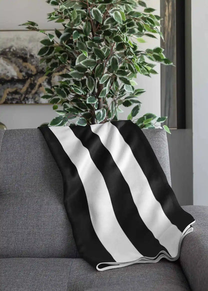 Vertical Stripes digital art print on a throw blanket placed over a couch, featuring bold black and white vertical lines in a minimalist design, enhancing contemporary home decor.