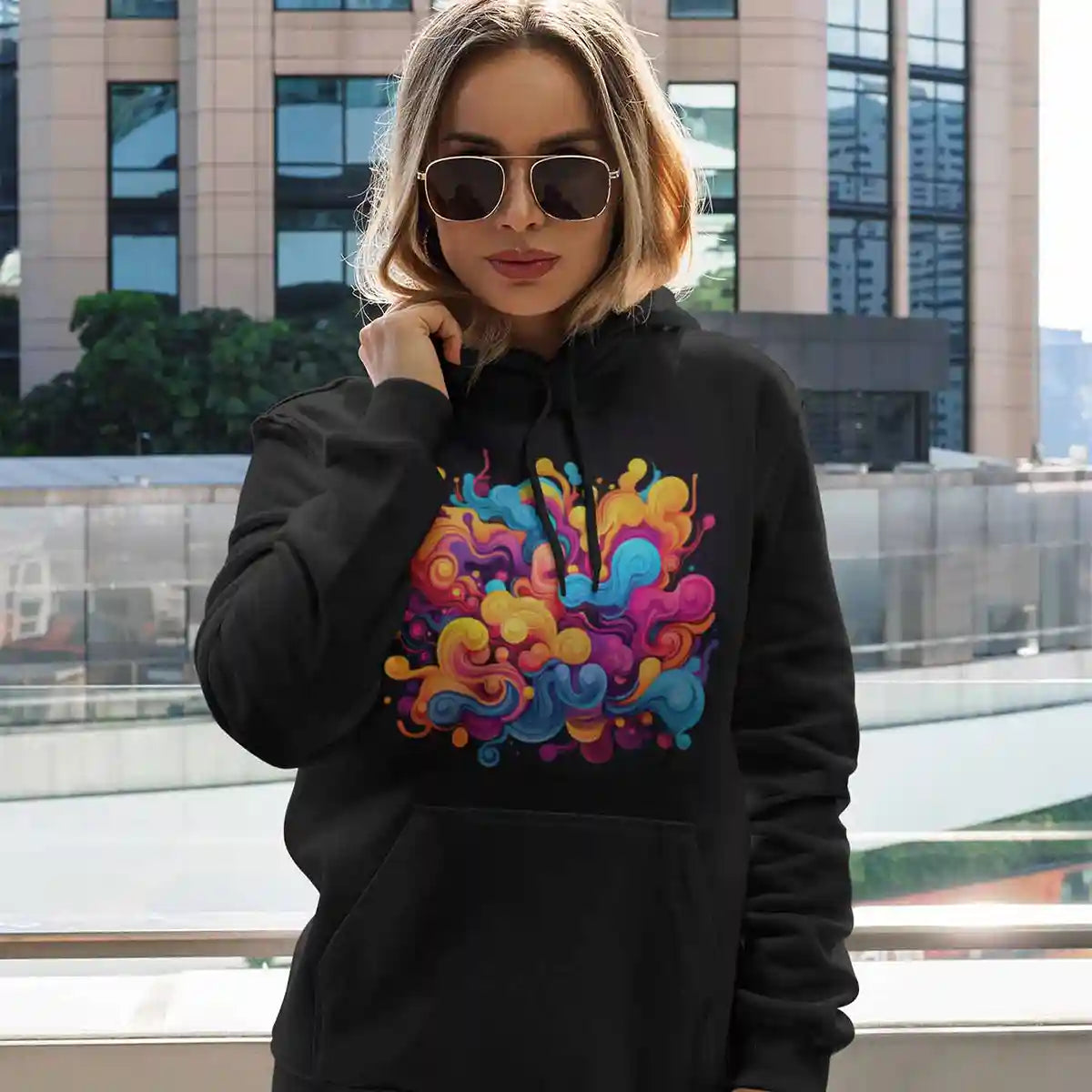 Pullover hoodie featuring Vivid Waves digital art print worn by woman near tall building.