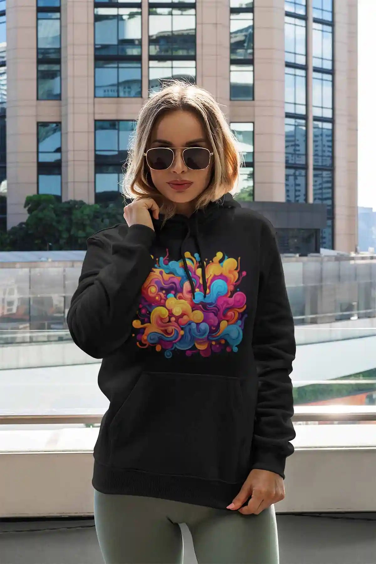 Vivid Waves digital art print on a pullover hoodie, featuring a woman posing by a tall building, showcasing dynamic colors and modern abstract patterns.